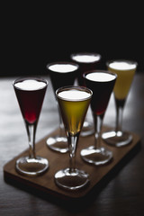 many glasses of shot or liqueur. Friends drink shot or liqueur and cheers. alcohol on blurred table background. Party and toast concept.