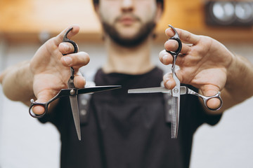 professional barber tool: sharpened scissors held by a haircut master in a modern barber shop. A concept for barbershops, beauty salons and hairdressers