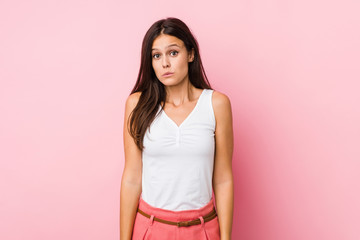 Young cute woman shrugs shoulders and open eyes confused.