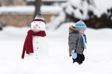 Snowman and boy outdoors. Freedom childhood leisure activities