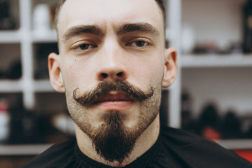 stylish attractive man with a beard in a barbershop. Shaving and modeling a contemporary beard...