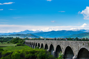 Fototapeta na wymiar Montenegro, Historical building emperors bridge architecture of stone arches in green nature landscape of niksic city surrounded by mountains