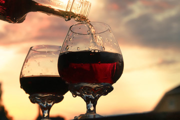 Fototapeta na wymiar Pour into a glass of wine from a bottle. Evening. Summer. Sunset. Celebrate a birthday in nature.
