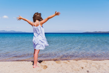 Fototapeta na wymiar Cute little girl looking at sea on beautiful tropical beach. Summer, fun and vacations concept 