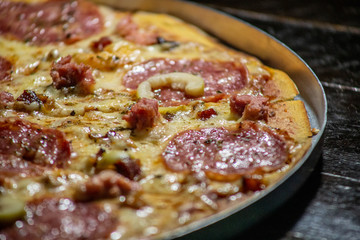 Homemade hot pepperoni pizza ready to eat on a wooden table and aluminum tray