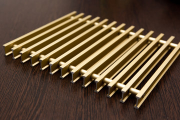 On a dark table lies a lattice of gold-plated metal strips connected by inserts.