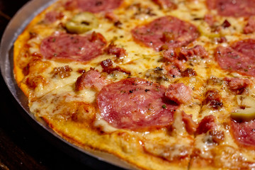 Homemade hot pepperoni pizza ready to eat on a wooden table and aluminum tray