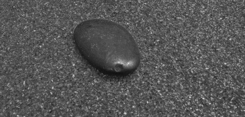 Fototapeta na wymiar single river stone in fine ornamental sand with chromium shards