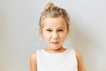 Negative human emotions and reaction. Isolated shot of displeased annoyed little girl grimacing...