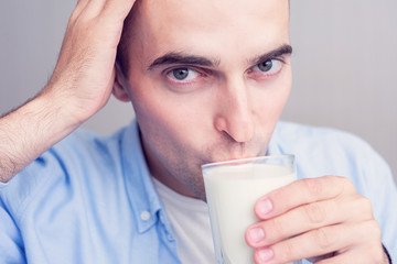 Happy young man drinking milk, portrait, closeup, toned