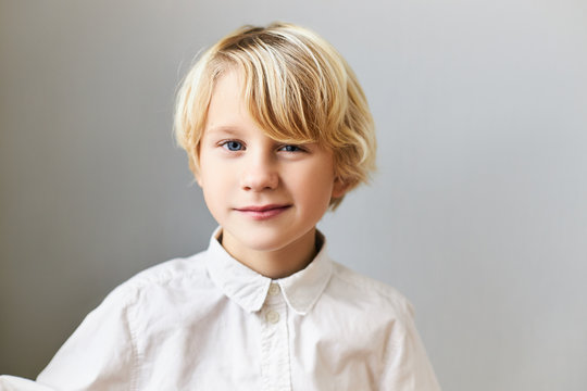 Isolated image of emotional cheerful blue eyed Caucasian boy with fair hair having playful facial expression, winking at camera. Children, spontaneity, happy childhood and positive emotions