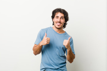 Fototapeta premium Young handsome man against a white background raising both thumbs up, smiling and confident.