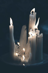 Set of white candles lit.  Twinkling candle light, dark background