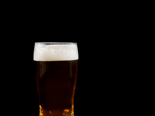 Glass with dark beer on black background