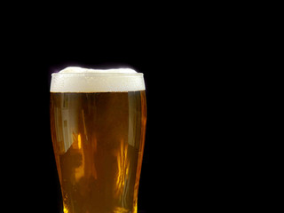 Glass with dark beer on black background