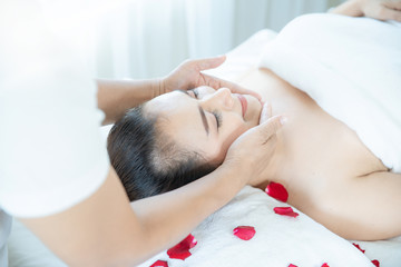 Fototapeta na wymiar Beautiful woman taking a spa facial. Beautiful female taking facial massage treatment in the spa salon. Young female with close eyes taking skin care with face massage in spa.