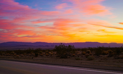 Beautiful sunrise sunset dusk dawn over lonely empty country road highway street in the desert Joshua Tree Monument National Park with fire sky - obrazy, fototapety, plakaty