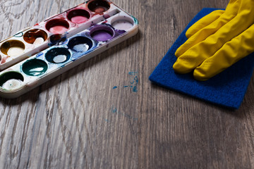 Woman cleans the table stained with paint. A stain from the paint palette. housewife, housework, cleaner, wash,