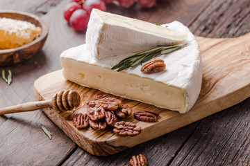Segment of Brie cheese or soft cow's - French camembert  on wooden board with  grapes, honeycomb...