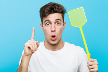 Young caucasian man holding a fly swatter having some great idea, concept of creativity.