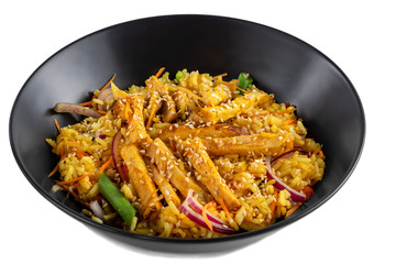 Sliced grilled chicken breast, white rice in sauce, vegetables and sesame seeds in a black plate isolated on white background, side view