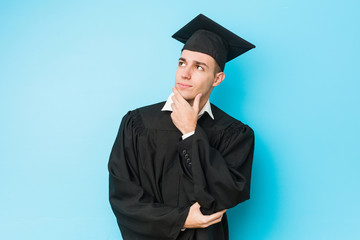 Young caucasian graduated man looking sideways with doubtful and skeptical expression.