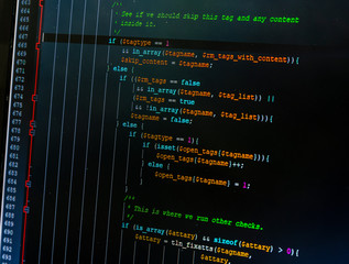 Web developer PHP code close up. The editing program colors the individual elements of the code against a dark background. Screen image.