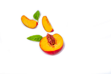 Slices of smooth-skinned ripe nectarines (peaches) with leaves isolated on a white background. Top view, flat lay, copy space for text.