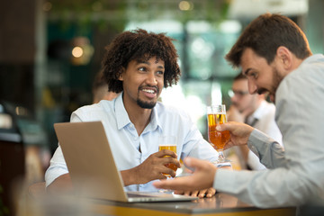 Young businessmen siting pub and drinking beer as they work