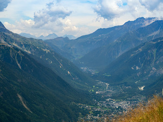 Fototapeta na wymiar The city is located in the Alps valley. High mountains rise around. The slopes of the mountains are green.