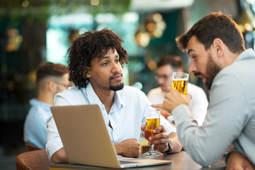 Young businessmen siting pub and drinking beer as they work
