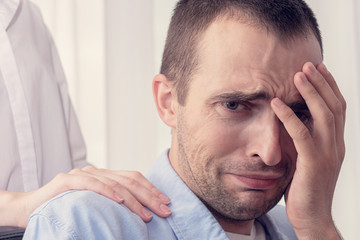 Obraz premium Concept of abuse and psychological violence in the family. The man is afraid and crying, the wife in the background, close up, toned