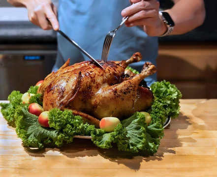 Hands cutting roast capon (turkey,chicken) on the kitchen table