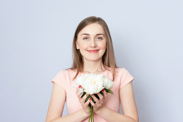 Beautiful young woman with white peonies smiling, portrait, toned