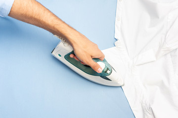 Person ironing clean shirt, men's hands, closeup, top view, toned
