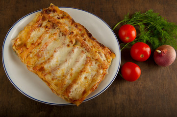 Plate of Spanish cannelloni with vegetables, tomato, onion and dill