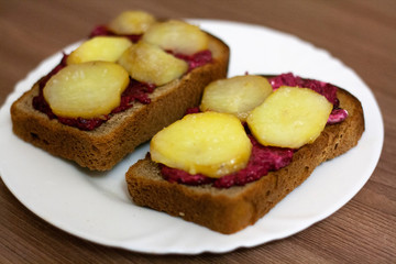 Black bread sandwiches with beets and potatoes on a white plate