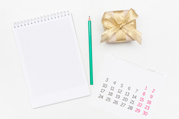 Notebook, gift box with gold ribbon, pencil and calendar, copy space, top view
