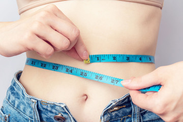 Woman measures the girth around the waist measuring tape. Concept of diet and body weight control, close up, toned
