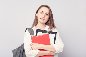 Attractive girl student with notebooks. Concept of education. Portrait, grey background, copy space, slogan, toned