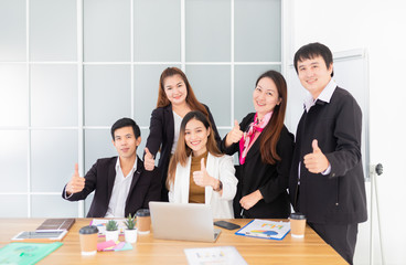 asian officer group show thumbs up sign with hands together when looking success project result in laptop, they feeling happy and fun in office, happiness workplace