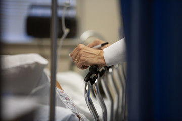 Cropped image of doctor standing by patient on bed at hospital