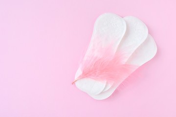 Daily soft cotton pads with pink feathers on neutral background with empty space for text. Menstrual pad. Women's health concept monthly period days. Woman critical days, menstruation cycle 