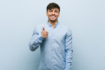 Young hispanic business man smiling and raising thumb up