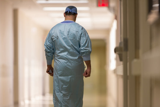 Rear View Of Surgeon Walking Down Hospital Corridor