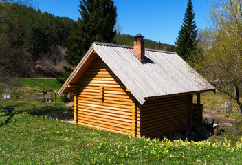 Obraz premium New log-house made by old technologies in a green meadow by the river. Beautiful natural background, log wall pattern.