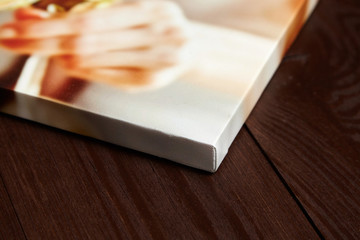 Canvas photo print on brown wooden background. Sample of gallery wrapping method of canvas...