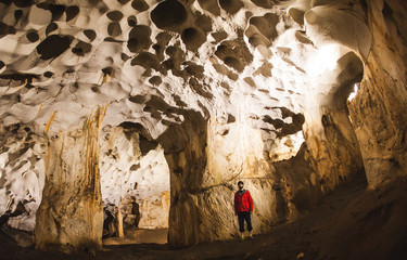A man with a backpack stands in the middle of the cave.