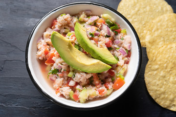 Mexican fish  ceviche with avocado on dark background