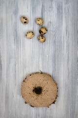 Collection of ripe sunflower flowers and quail eggs on a light surface. Postcard for autumn with warm wishes of a successful harvest.